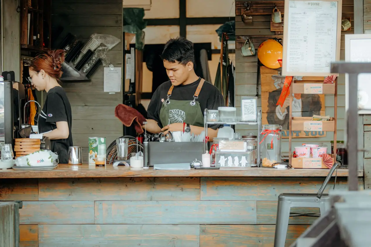 Two staff working behind a small coffee shop counter