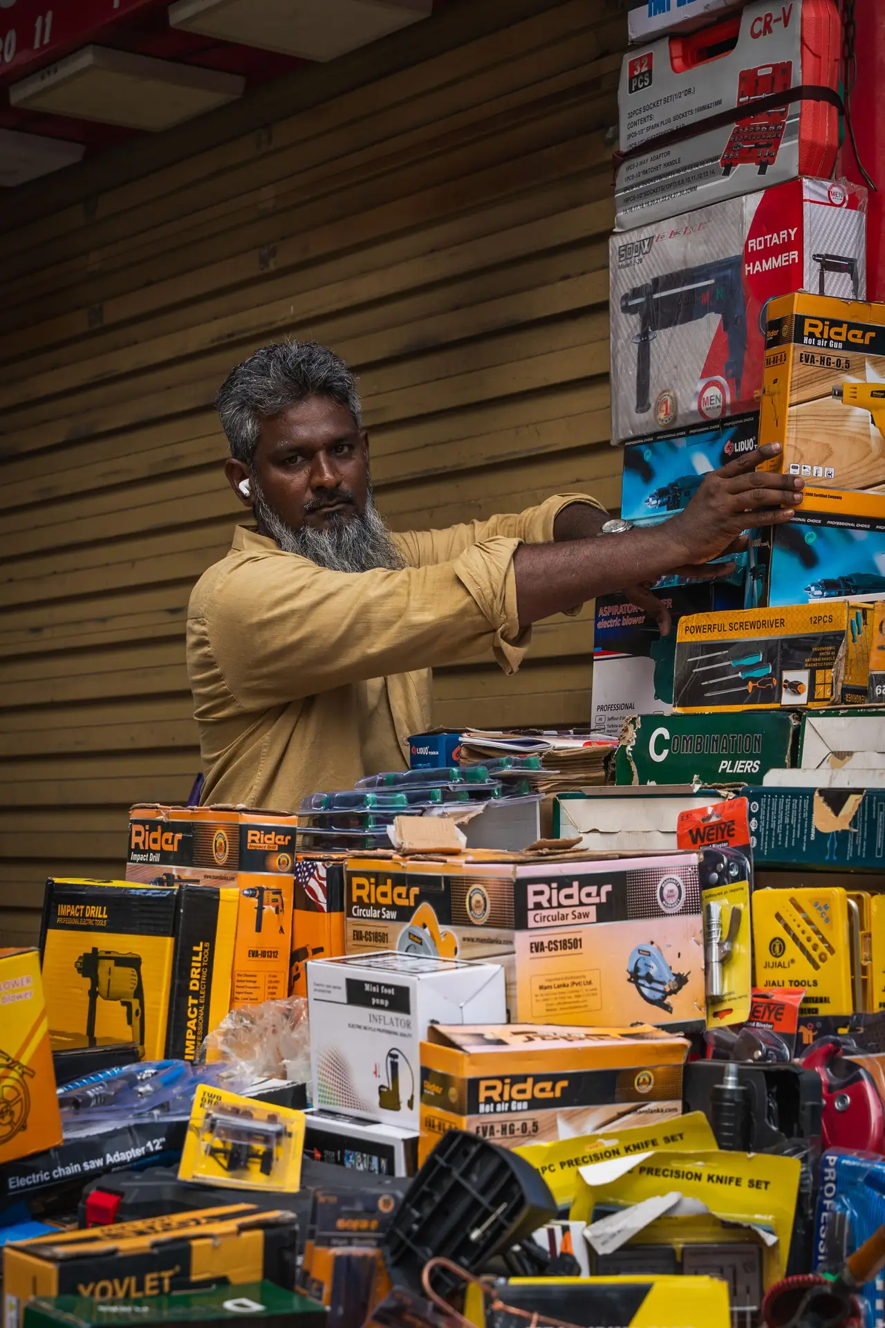 A hardware trader stacking boxed power tools at his counter